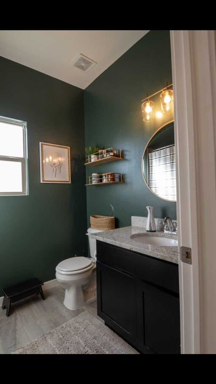 a bathroom with dark green walls and white counter tops, along with a black vanity