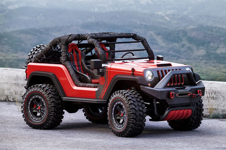 a red and black jeep parked on top of a hill