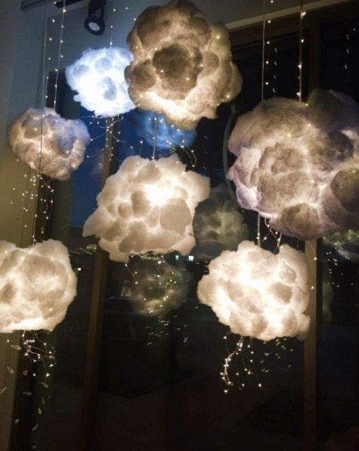 some clouds that are hanging from the ceiling in front of a window with lights on them