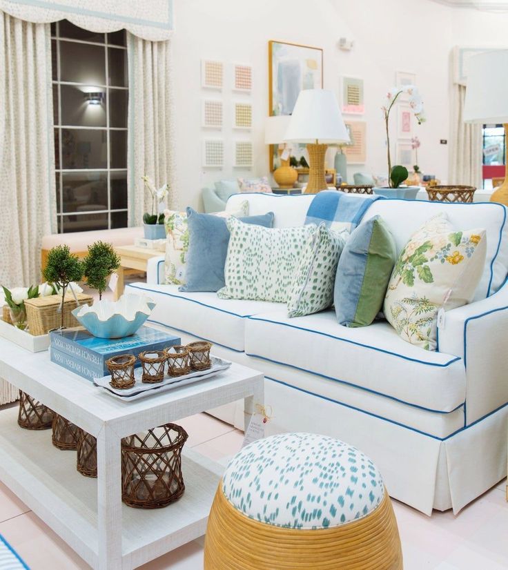 a living room filled with white furniture and lots of pillows on top of it's couches