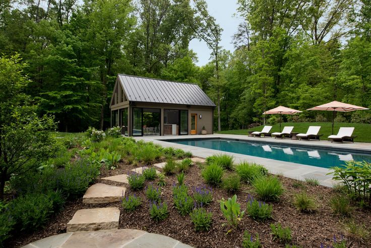 an outdoor swimming pool surrounded by trees and lawn chairs