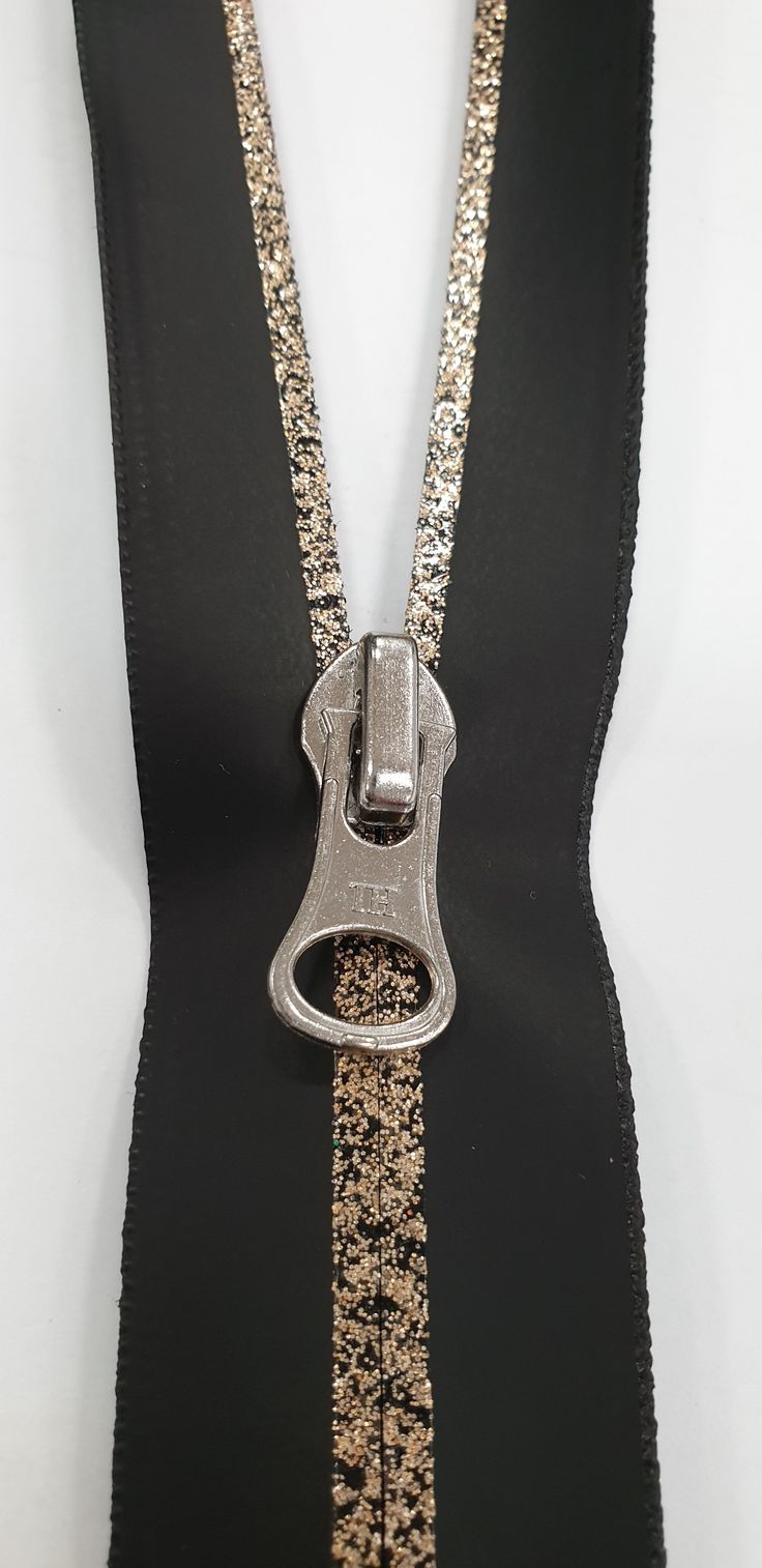 an open zipper with gold sequins and a metal clip on it's side