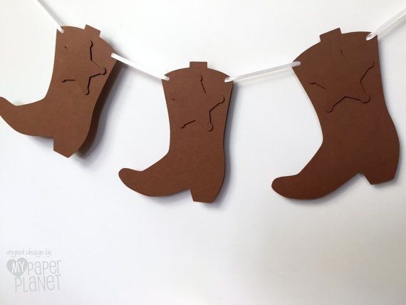 some brown paper cutouts are hanging on a line with clothes pins in the shape of boots