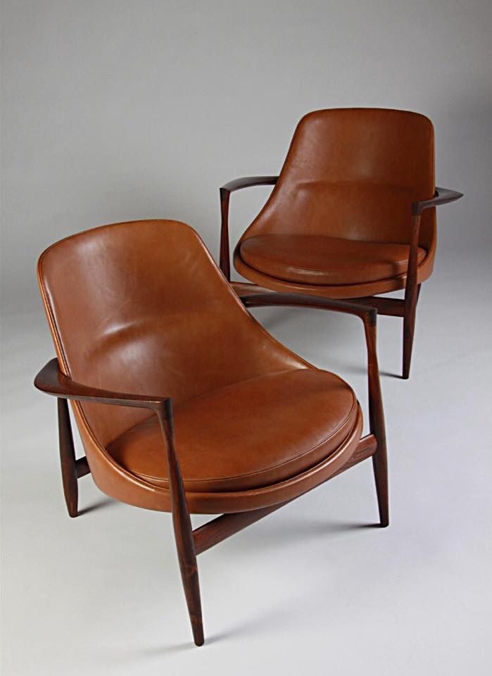 two brown leather chairs sitting next to each other on top of a white flooring