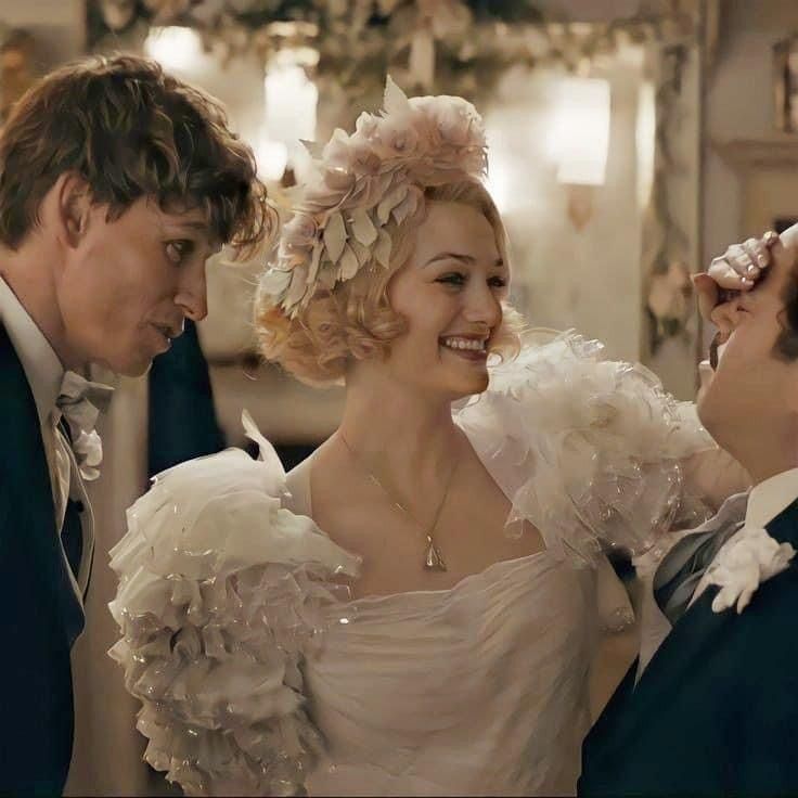 two men and a woman dressed up in period clothing looking at each other while smiling