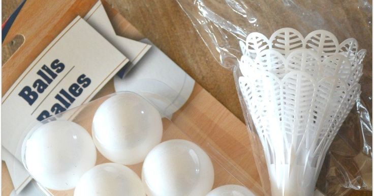 some white plastic balls are sitting on a wooden table next to a package of golf tees