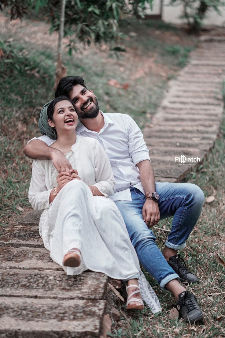 a man and woman are sitting on the steps in front of each other, smiling