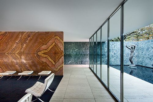 a room with glass walls and chairs in front of the wall that is reflecting water