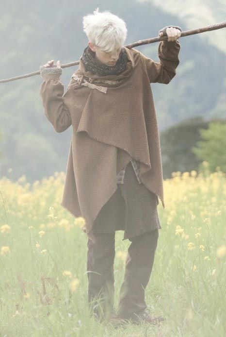 an old woman with white hair holding a stick in her hand while standing in a field