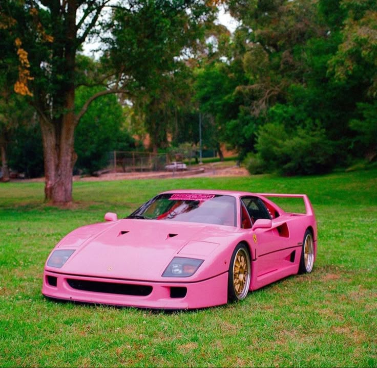 a pink sports car parked in the grass