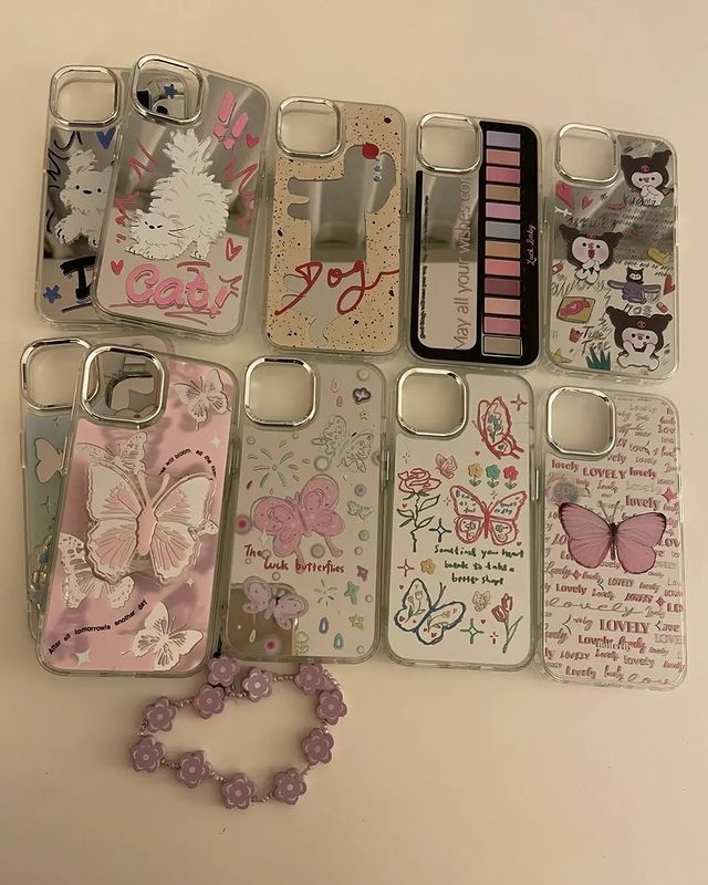 several cell phones are lined up next to each other on a white surface with pink flowers and butterflies