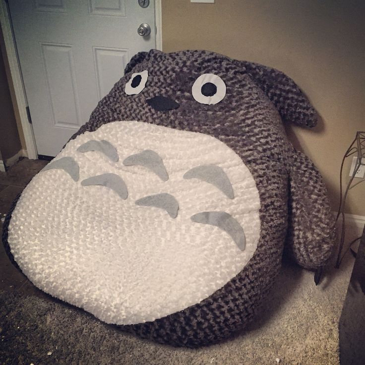 a stuffed animal sitting on the floor in front of a door with eyes and nose