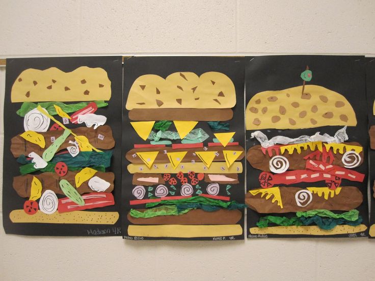 three cardboard cutouts of sandwiches and hamburgers are displayed on a white wall in an art gallery