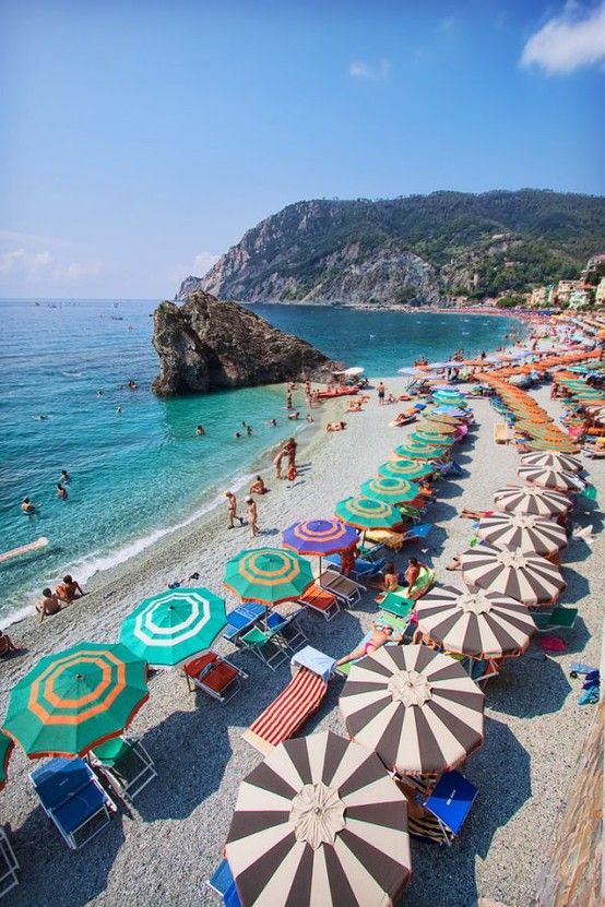 the beach is crowded with umbrellas and people swimming in the water at this time