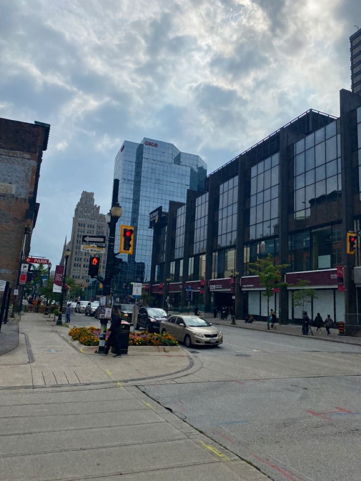 an intersection with cars and people walking on the sidewalk in front of some tall buildings