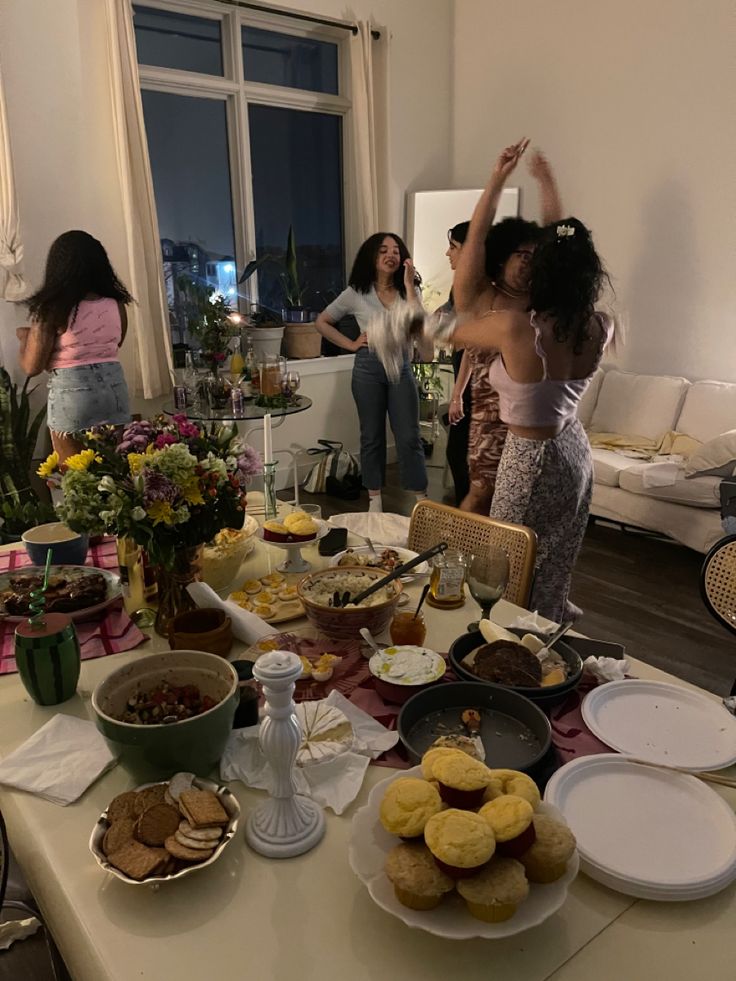 two women standing in front of a table filled with plates and bowls full of food