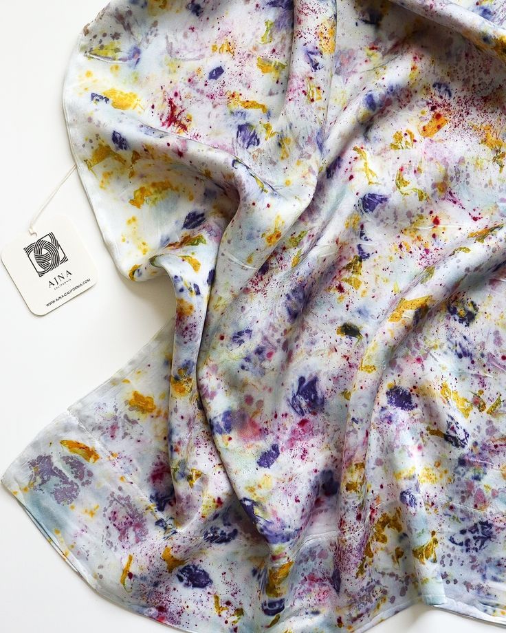 a white scarf with multicolored paint splattered on it and a tag