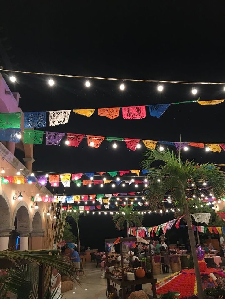 colorful lights strung from the ceiling above tables and chairs in an outdoor restaurant at night