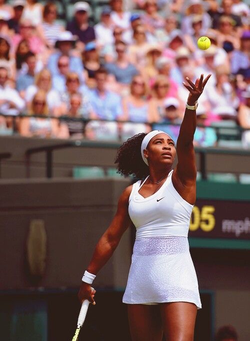 a female tennis player is serving the ball in front of an audience at a tennis match