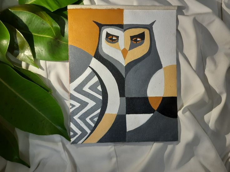 an owl painting on a white sheet next to a green plant