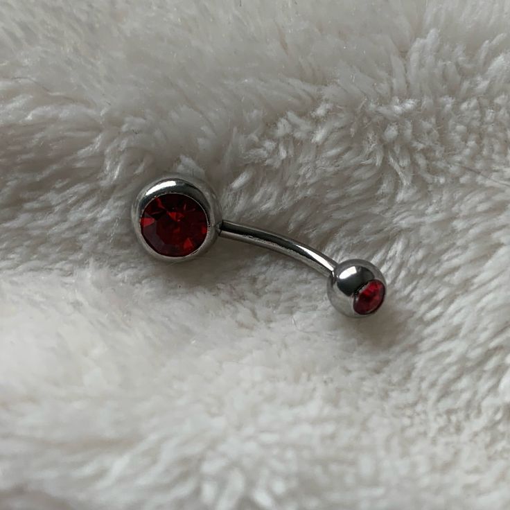 a pair of red jeweled nose piercings on white fur