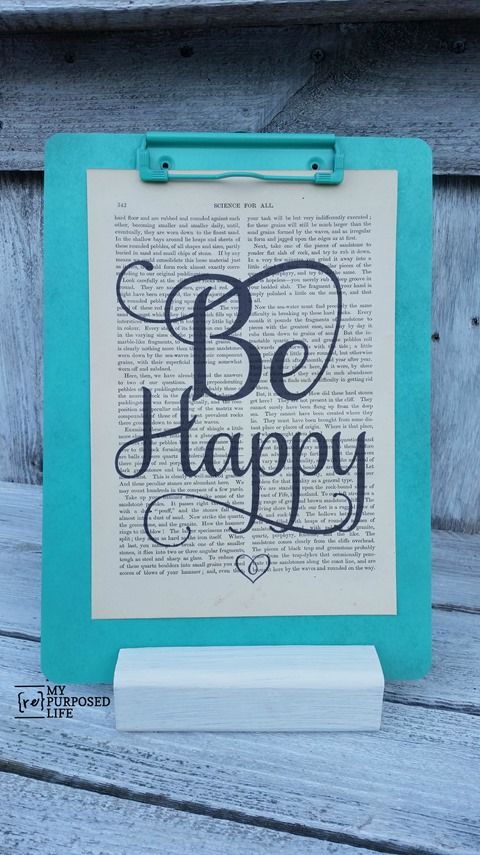 an open book with the words be happy on it, and a clip board stand