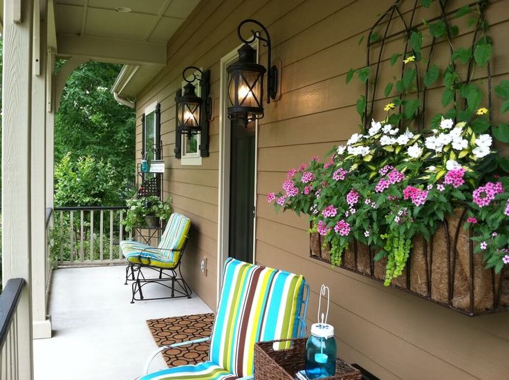 the front porch is decorated with flowers and chairs