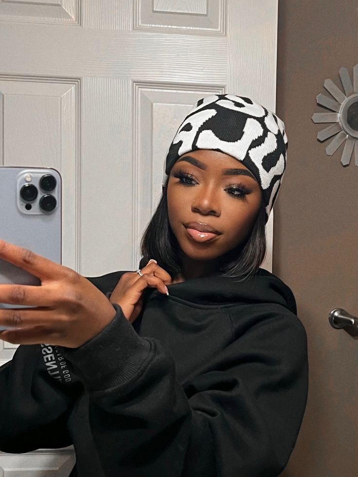 a woman taking a selfie in front of a white door with her cell phone