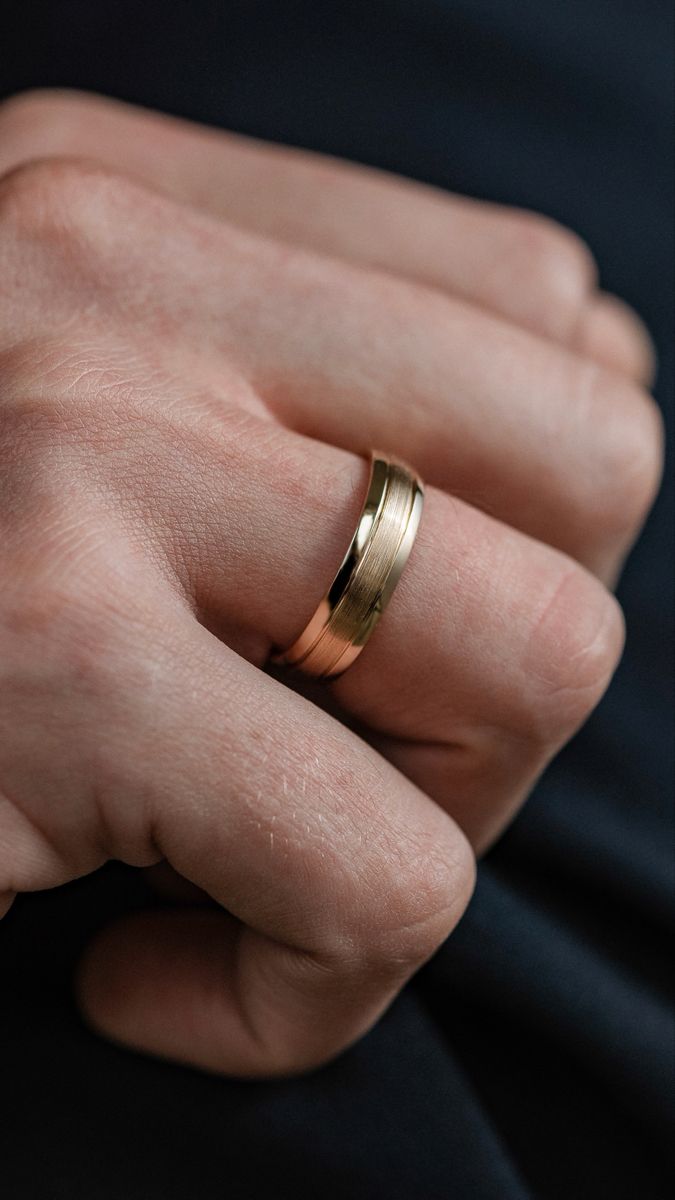 a person wearing a gold wedding band in their hand