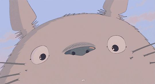 a close up of a cartoon character with big eyes and an animal like face in the background