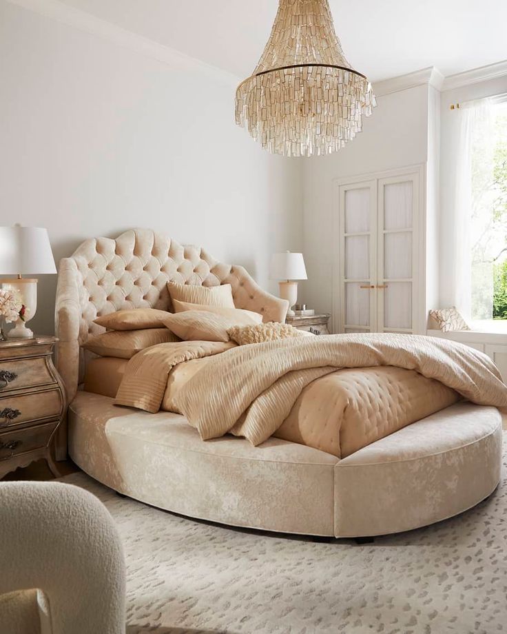 a large round bed sitting in a bedroom under a chandelier