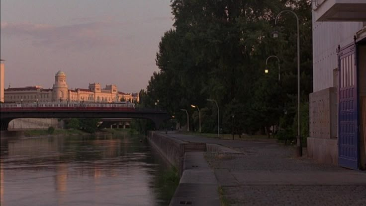 a bridge over a body of water with buildings in the background and trees on either side