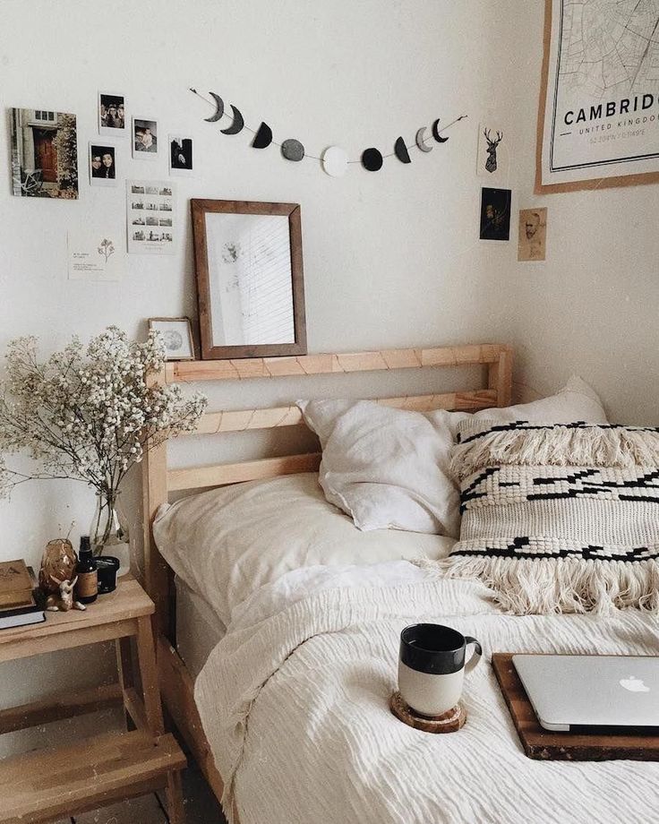 a bed with white sheets and pillows next to a laptop on top of a wooden table