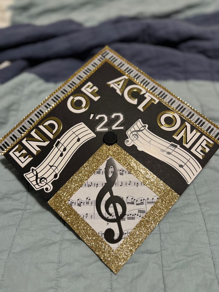 a black and gold graduation cap with musical notes on it that says end of act one