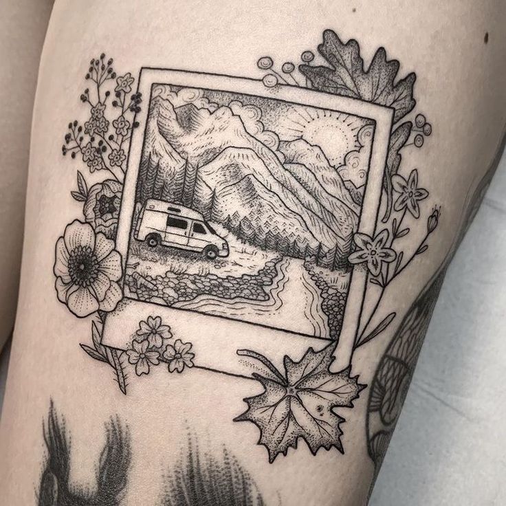 a woman's thigh with an image of a van and flowers in the frame