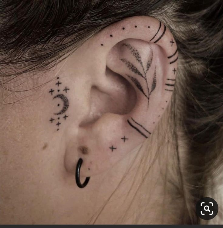 a woman's ear with tattoos on her left side and an arrow in the middle