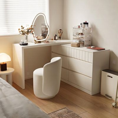 a bedroom with white furniture and accessories on the dresser next to a mirror, lamp, and window