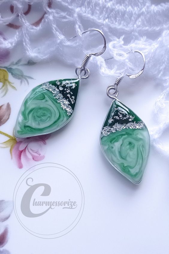 the earrings are made with green glass and silver metal wire, on a white background