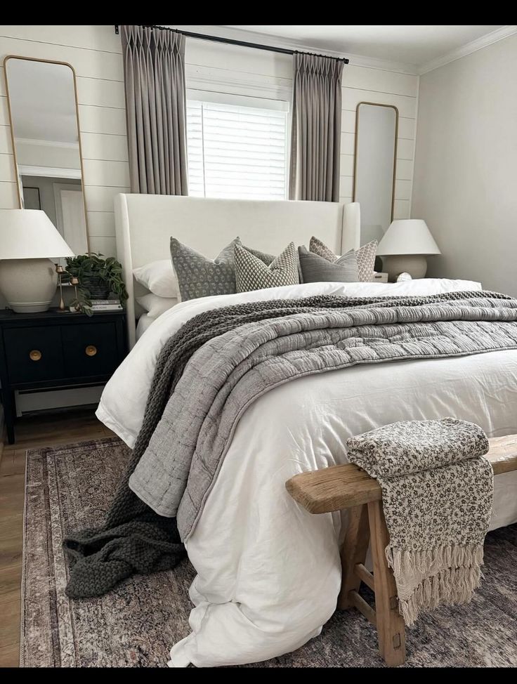 a white bed sitting in a bedroom on top of a wooden floor next to two lamps