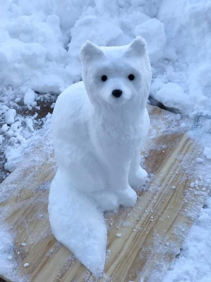 a white polar bear statue sitting on top of snow covered ground and wooden planks