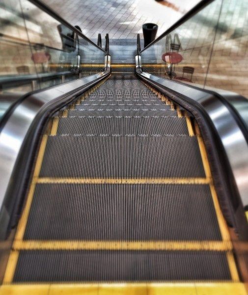 an escalator in a subway station with metal railings and yellow lines on the ground