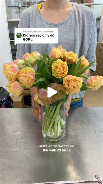 a vase filled with yellow flowers sitting on top of a table next to a woman