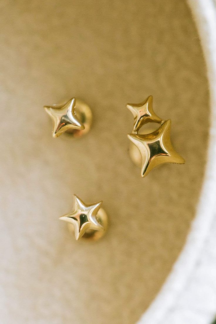 three gold star studs sitting on top of a white bowl