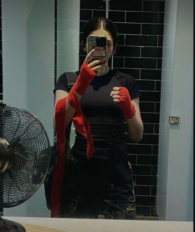 a woman taking a selfie in front of a mirror with her red gloves on