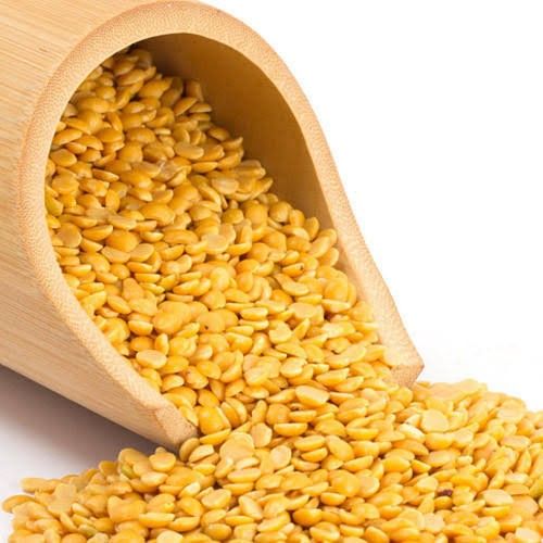 corn kernels are spilling out of a wooden scoop into a white background, with the top section partially open