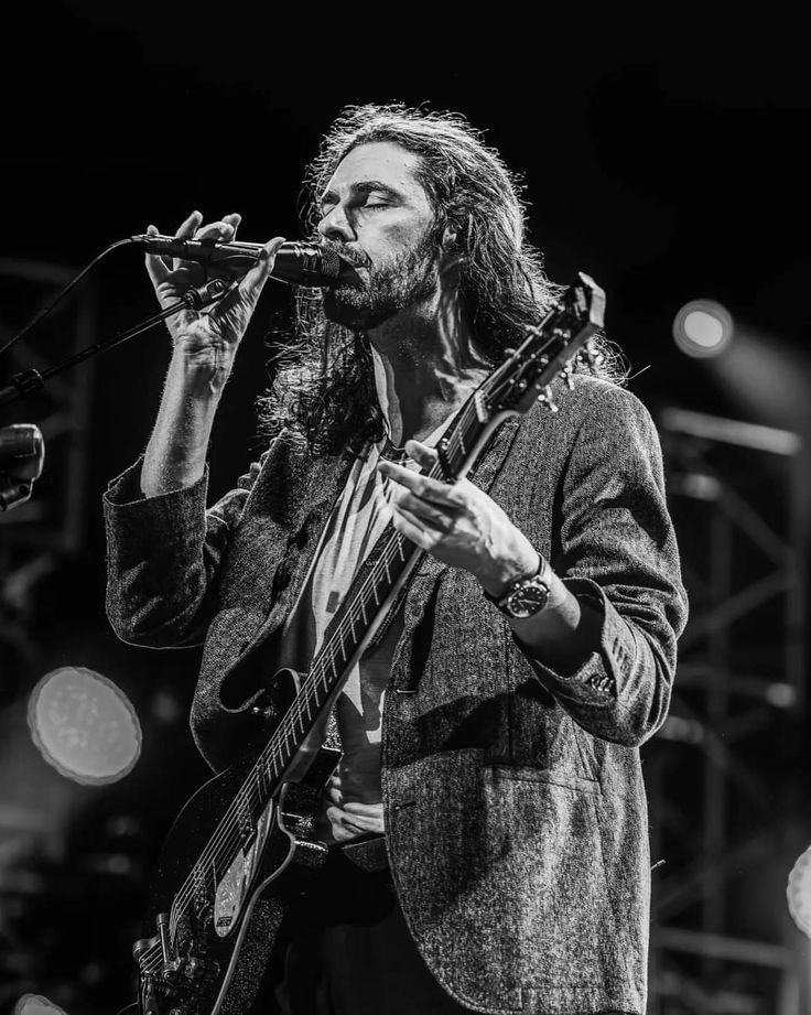 a man that is standing up with a guitar in his hand and singing into a microphone