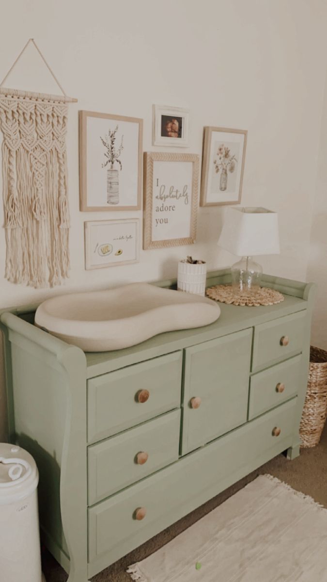 there is a green dresser with pictures on the wall