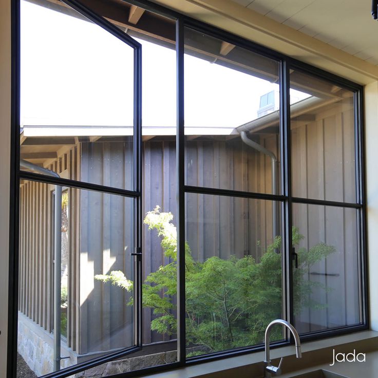 an open window in a kitchen with trees outside the window and a sink below it