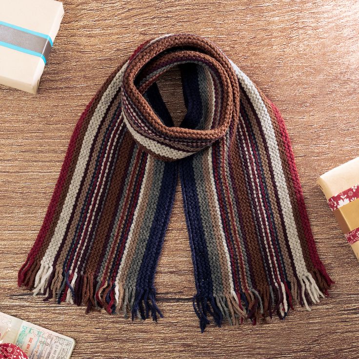 a scarf and other items laid out on a wooden table next to each other,