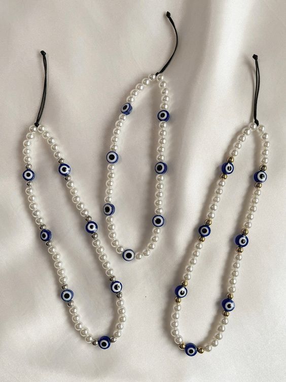 three necklaces with evil eyes on them